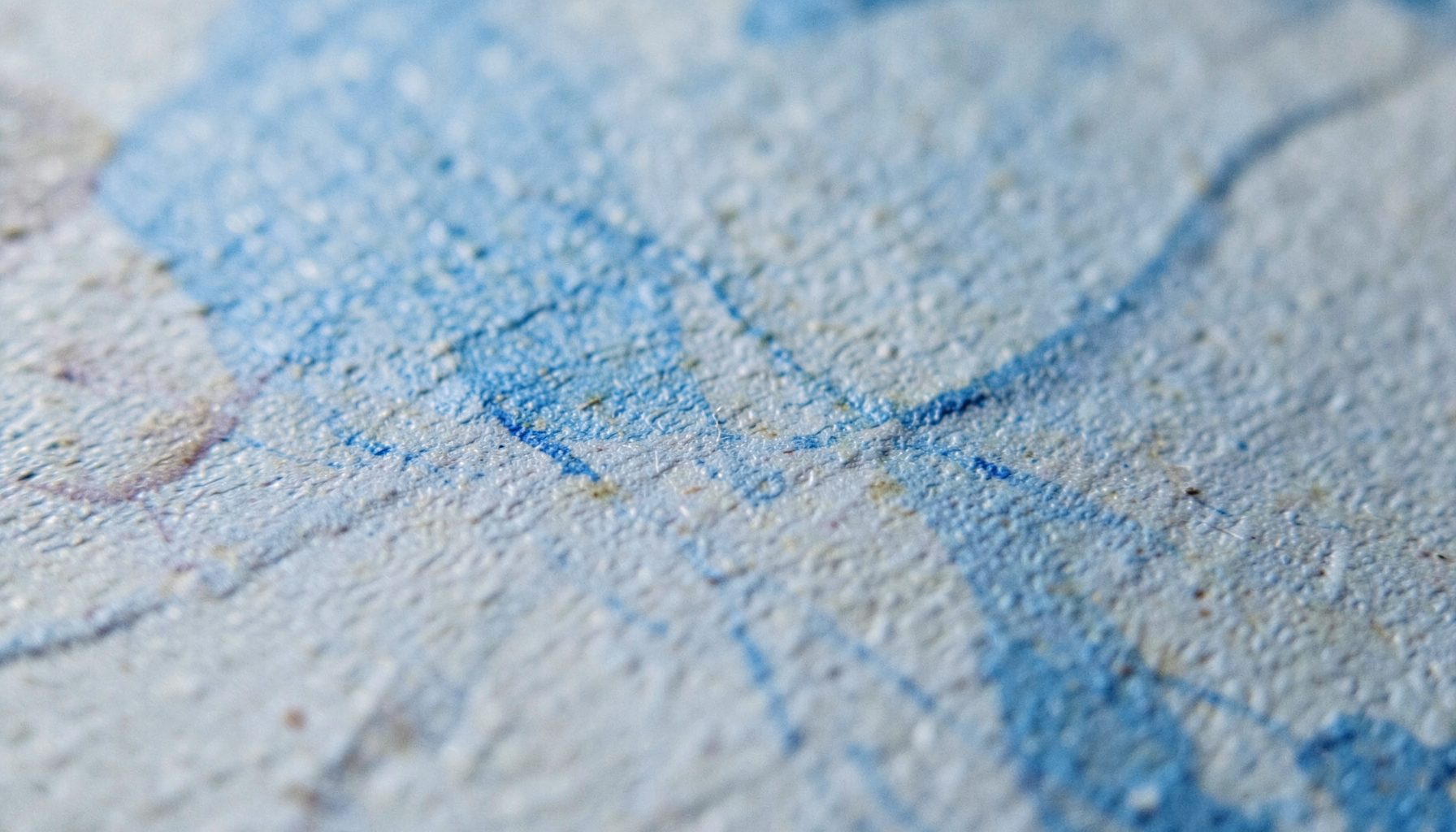 An extreme close-up of textured matte paper with subtle grain, muted earth tones, and faint ink impressions suggesting a photographic print