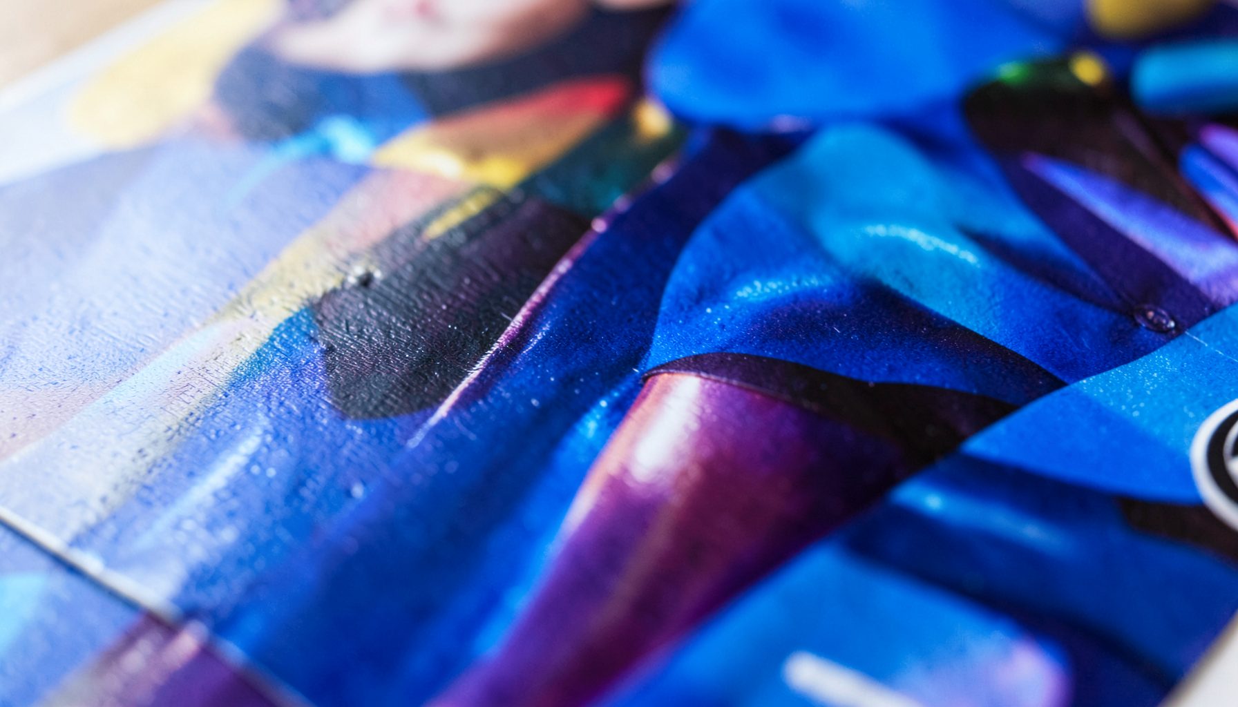 A close-up of glossy magazine paper with vibrant ink, showing a fashion editorial spread with rich jewel tones and subtle light reflections on the coated surface