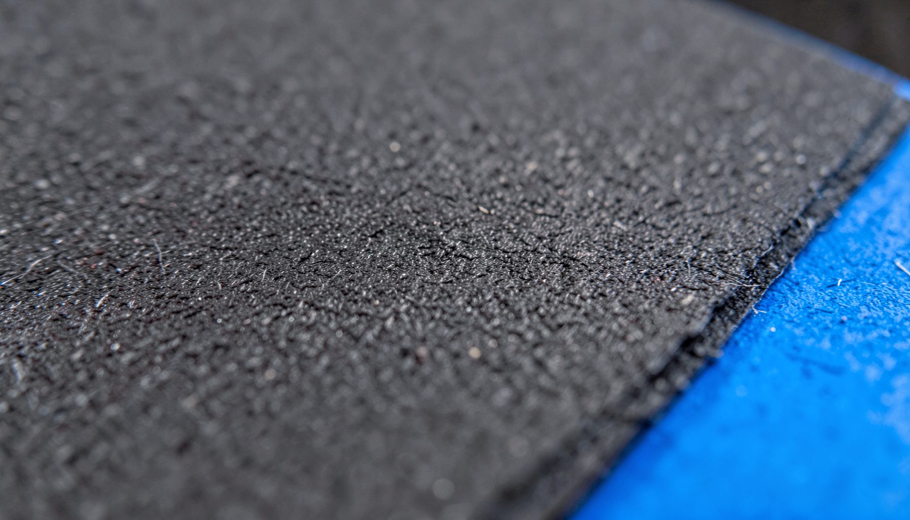 Close-up of textured charcoal paper with fine grain in dark grey tones and a focused, studio-like mood
