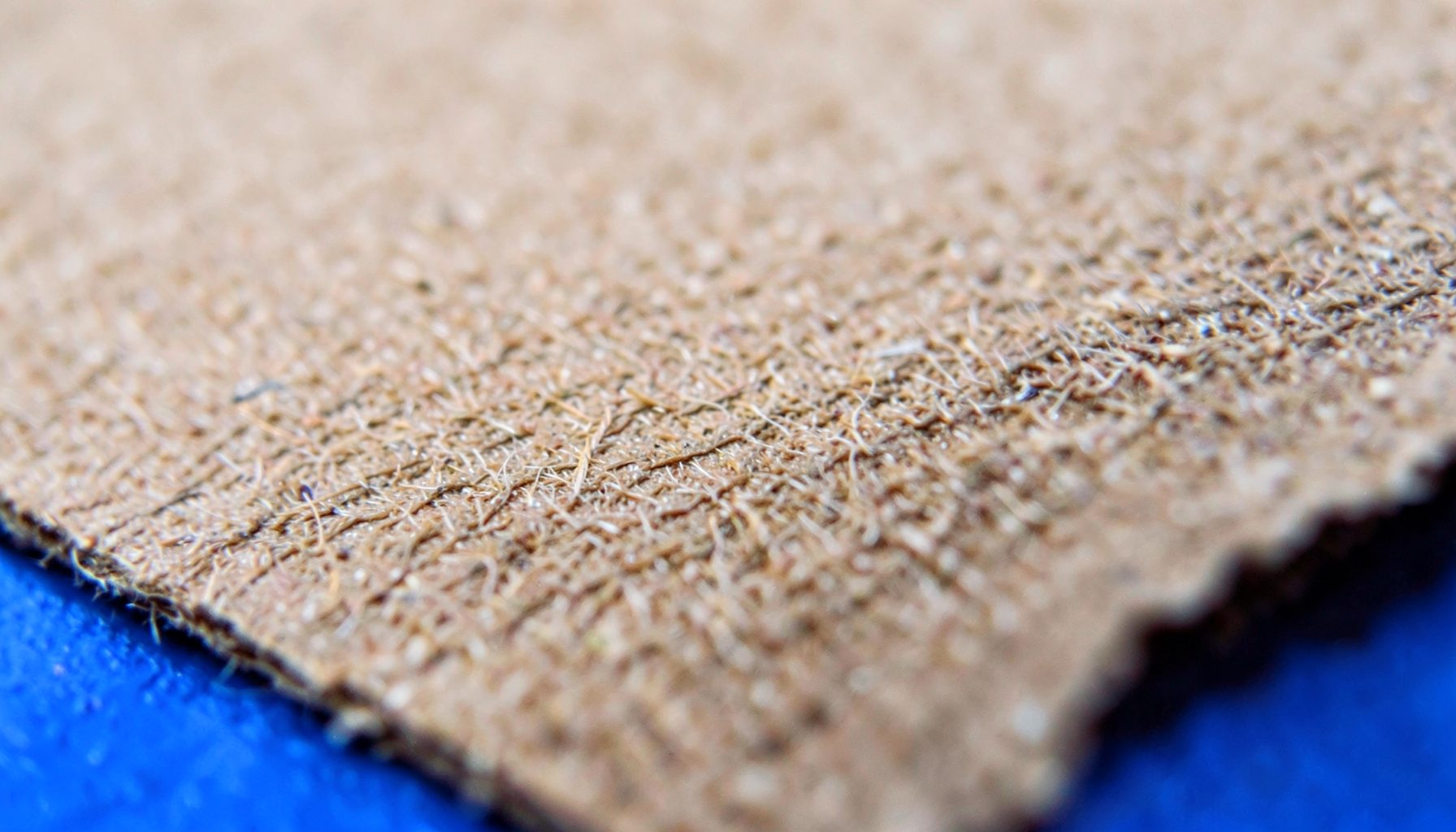 An extreme close-up of uncoated kraft paper, showing fine brown fibers and a slightly rough, matte surface.